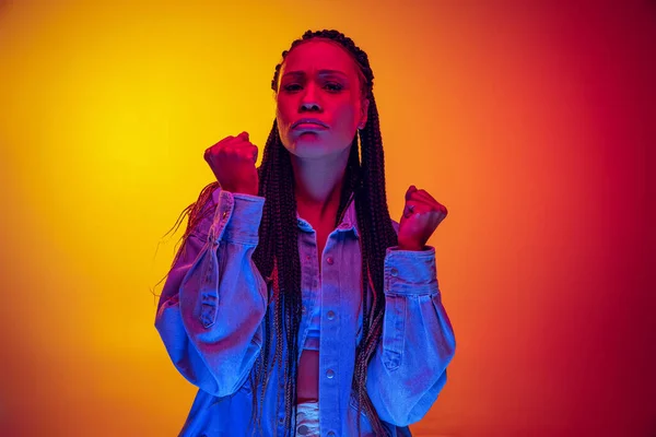 Retrato de cerca de una chica ofendida mirando a la cámara aislada sobre fondo rosa amarillo con luz de neón. Concepto de belleza, arte, moda, juventud y emociones — Foto de Stock