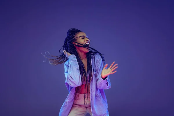 Menina africana emocional em jeans e dança camisa, se divertindo isolado em fundo azul escuro. Conceito de beleza, arte, moda, juventude e emoções — Fotografia de Stock