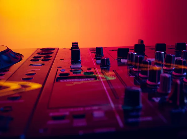 Close-up image of professional dj sound mixer isolated over gradient red yellow background in neon light — Foto de Stock