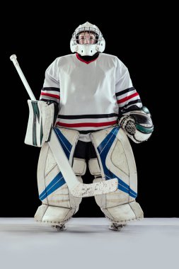 Erkek, çocuk, hokey oyuncusu, özel formalı, siyah stüdyo arka planında yalnız poz veren bir kaleci.