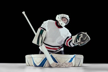 Genç bir çocuğun portresi, hareket halindeki bir hokey oyuncusu, siyah stüdyo arka planında izole edilmiş bir eğitim. Motivasyonu sürdürmek