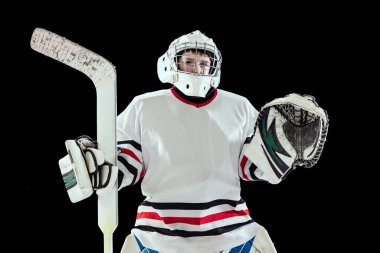 Siyahi stüdyonun arka planında yalnız poz veren kaleci üniformalı çocuk, çocuk ve hokey oyuncusunun yarım boy portresi.