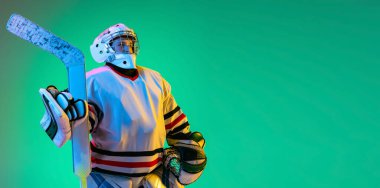 Çocuk portresi, çocuk, hokey oyuncusu üniformalı kaleci yeşil arka planda izole poz veriyor neon ışıkta