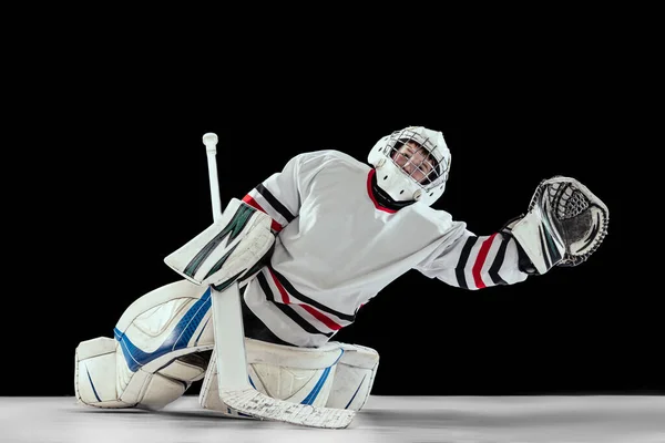Portrait of teen boy, hockey player, goalkeeper catching plug in motion isolated over black studio background. Dynamic sport. — 스톡 사진
