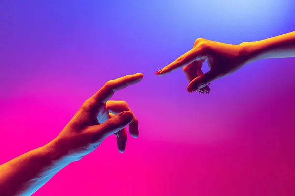 Zwei menschliche Hände, die sich isoliert auf einem blau-rosa Hintergrund im Neonlicht zu berühren versuchen. Konzept menschlicher Beziehung, Zusammengehörigkeit, Symbolik, Kultur und Geschichte — Stockfoto