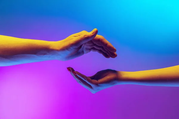 Two authentic hands trying to touch each other isolated on gradient blue purple background in neon light. Concept of relationship, community, care, support, symbolism, culture — Fotografia de Stock