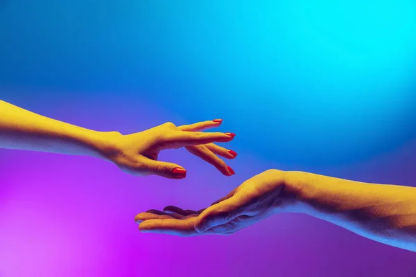 Two authentic hands trying to touch each other isolated on gradient blue purple background in neon light. Concept of relationship, community, care, support, symbolism — Fotografia de Stock