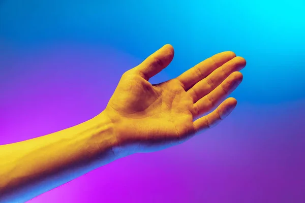 Estudio plano de mano humana aeténica aislada sobre gradiente púrpura-azul de fondo en luz de neón. Concepto de relación humana, comunidad, unidad — Foto de Stock