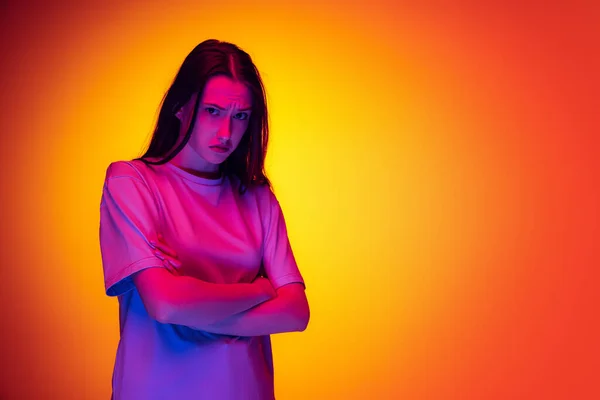 Halve lengte portret van jong charmant meisje, student met lang haar poseren geïsoleerd op oranje achtergrond in neon licht, filter. Concept van emoties, jeugd, schoonheid — Stockfoto