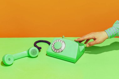 Colorful bright image of old-fashioned green colored phone isolated over orange background