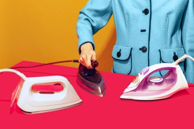 Sarı arkaplan üzerine izole edilmiş eski demirle pembe masa örtüsünü ütüleyen kadının renkli parlak görüntüsü