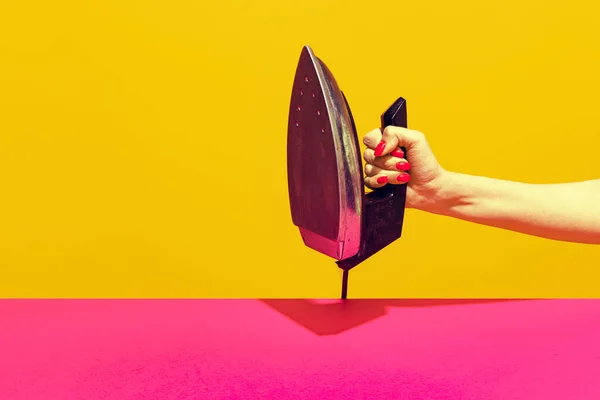 Colorful bright image of female hand holding retro iron isolated over pink yellow background — Foto de Stock