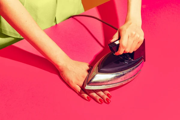 Colorful bright image of female hand ironing her hand with retro iron isolated over pink yellow background — Zdjęcie stockowe