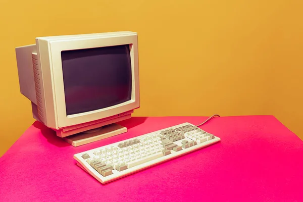Colorful image of vintage computer monitor and keyboard on bright pink tablecloth over yellow background — Foto de Stock