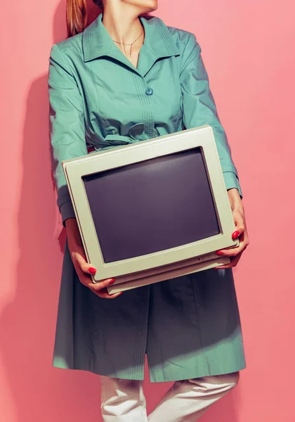Colorful image of woman holding retro computer monitor isolated over light pink background — Fotografia de Stock