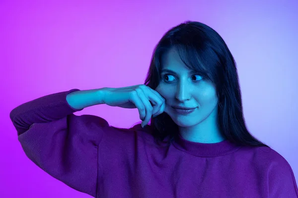 Молода смішна дівчина, яка робить божевільне обличчя ізольоване на фіолетовому студійному фоні в неоновому світлі. Поняття емоцій, вираження обличчя, мистецтво, краса — стокове фото