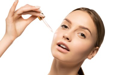 Serum süren genç ve güzel bir kadın, beyaz arka planda yağ izi var. Kozmetik, makyaj, doğal güzellik kavramı