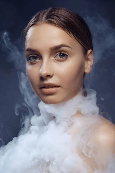 Portrait of beautiful young girl with clean, well kept skin isolated on dark background with smoke. Concept of beauty, art, ad, cosmetics — ストック写真