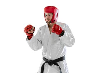 Beyaz dobok giyen, kasklı ve eldivenli beyaz arka planda izole edilmiş genç bir adamın portresi. Spor anlayışı, egzersiz, sağlık.