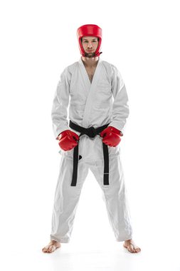 Portrait of young sportive man wearing white dobok, helmet and gloves posing isolated over white background. Concept of sport, workout, health.