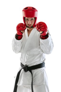 Portrait of young sportive man wearing white dobok, helmet and gloves practicing isolated over white background. Concept of sport, workout, health.