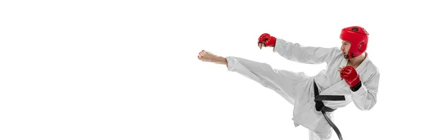 Retrato de jovem esportivo vestindo dobok branco, capacete e luvas praticando isolado sobre fundo branco. Conceito de esporte, treino, saúde. — Fotografia de Stock