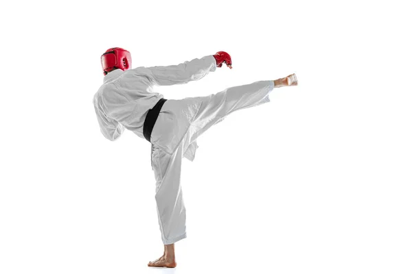 Vista traseira. Retrato de jovem esportivo vestindo dobok branco, capacete e luvas praticando isolado sobre fundo branco. Conceito de esporte, treino, saúde. — Fotografia de Stock