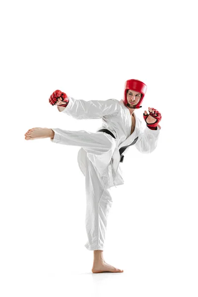 Portret van een jonge sportieve man met witte dobok, helm en handschoenen op een geïsoleerde witte achtergrond. Begrip sport, training, gezondheid. — Stockfoto