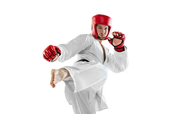 Portrait of young sportive man wearing white dobok, helmet and gloves practicing isolated over white background. Concept of sport, workout, health. — Photo