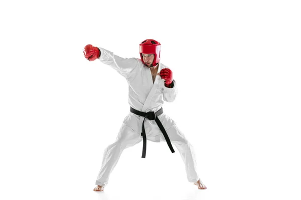 Retrato de jovem esportivo vestindo dobok branco, capacete e luvas praticando isolado sobre fundo branco. Conceito de esporte, treino, saúde. — Fotografia de Stock