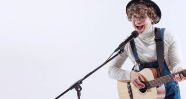 Genç bir adamın portresi, akustik gitar çalan ve şarkı söyleyen bir müzisyen. Sanat, müzik, tarz ve yaratılış kavramı