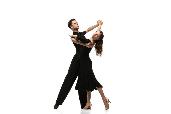 Dos jóvenes bailarines elegantes con trajes de escenario negro bailando bailes de salón aislados sobre fondo blanco. Concepto de arte, belleza, música, estilo. — Foto de Stock