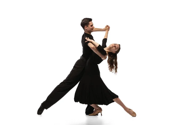 Two young graceful dancers wearing black stage outfits dancing ballroom dance isolated on white background. Concept of art, beauty, music, style. — ストック写真