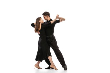 Two young graceful dancers wearing black stage outfits dancing ballroom dance isolated on white background. Concept of art, beauty, music, style.