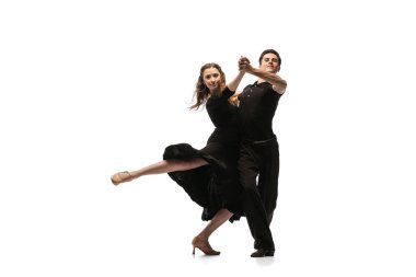 Portrait of young graceful dancers wearing black stage outfits dancing ballroom dance isolated on white background. Concept of art, beauty, music, style.
