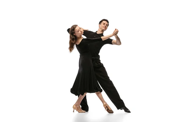 Two young graceful dancers wearing black stage outfits dancing ballroom dance isolated on white background. Concept of art, beauty, music, style. — Fotografia de Stock