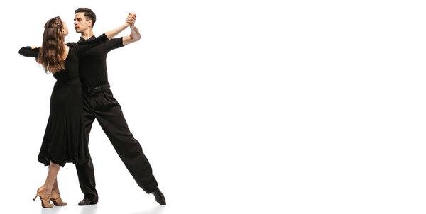 Flyer. Two young graceful dancers wearing black stage outfits dancing ballroom dance isolated on white background. Concept of art, beauty, music, style.