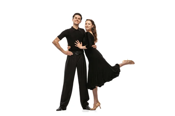 Two young graceful dancers wearing black stage outfits dancing ballroom dance isolated on white background. Concept of art, beauty, music, style. — ストック写真