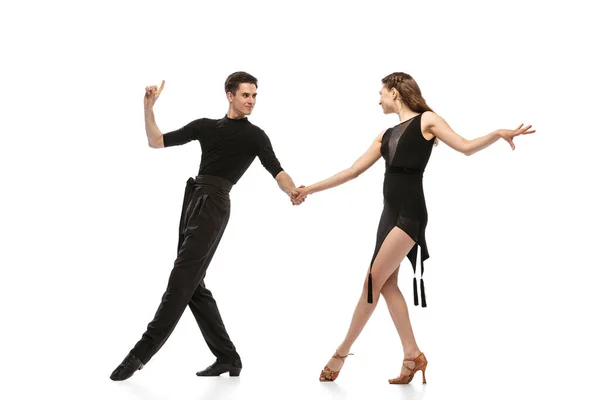 Dynamic portrait of young emotive dancers in black outfits dancing ballroom dance isolated on white background. Concept of art, beauty, music, style. — Stockfoto