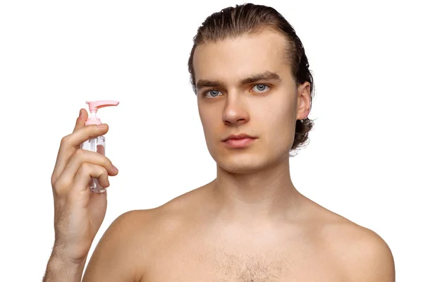 Portrait of young attractive man with perfect smooth skin, applying face cream isolated over white studio background. Cosmetics, health care, skin care, beauty — Stok fotoğraf