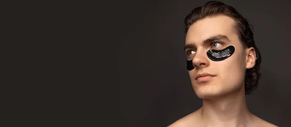 Young adorable man with well-kept skin using patches under eyes isolated over grey background. Fashion, cosmetics, health care, skin care, beauty — Fotografia de Stock