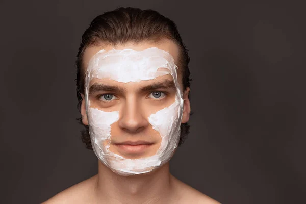 Moisturizing face mask. One man with perfect well-kept skin using face cream mask isolated over grey background. Cosmetics, health care, skin care, beauty — 스톡 사진