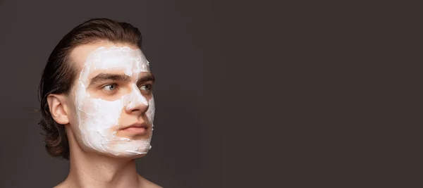 Moisturizing face mask. One man with perfect well-kept skin using face cream mask isolated over grey background. Cosmetics, health care, skin care, beauty — 스톡 사진