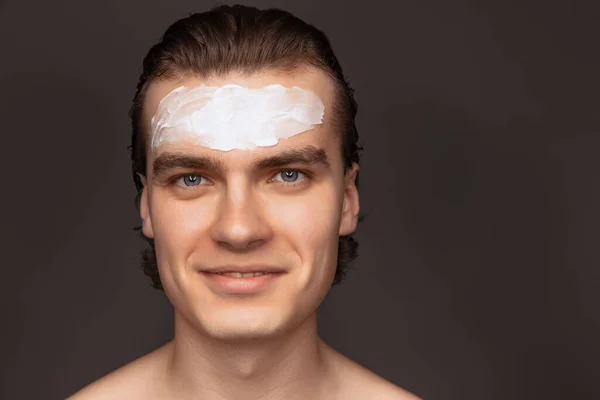 Moisturizing face mask. One man with perfect well-kept skin using face cream mask isolated over grey background. Cosmetics, health care, skin care, beauty — 스톡 사진