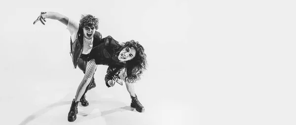 Studio shot of excited, astonished young boy and girl with bright makeup wearing black leather outfits moving on white background. Music, youth — Stock Fotó
