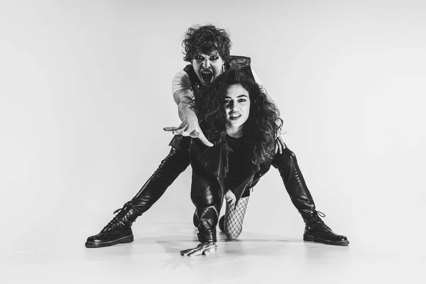 Studio shot of excited, astonished young boy and girl with bright makeup wearing black leather outfits moving on white background. Music, youth — Foto Stock