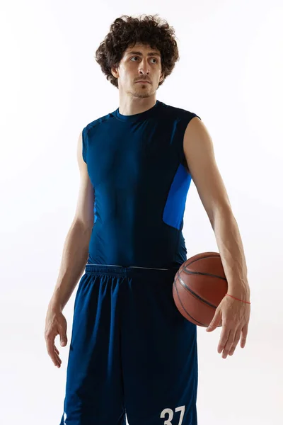 Porträt eines jungen muskulösen Basketballspielers, der isoliert auf weißem Hintergrund posiert. Konzept aus Sport, Bewegung, Energie und dynamischem, gesundem Lebensstil. — Stockfoto