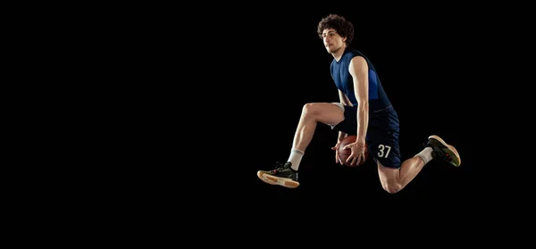 Professional basketball player in action and motion isolated on dark background. Concept of sport, competition, achievements, game. — Fotografia de Stock