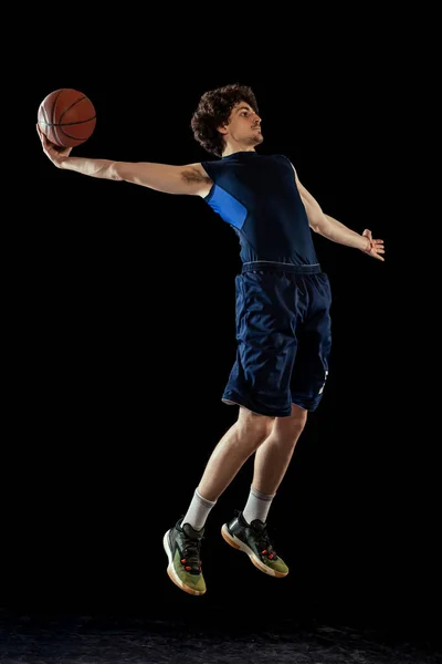 Basketballprofi in Aktion und Bewegung isoliert auf dunklem Hintergrund. Konzept des Sports, des Wettbewerbs, der Leistungen, des Spiels. — Stockfoto