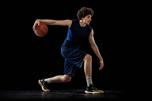 Basketballprofi in Aktion und Bewegung isoliert auf dunklem Hintergrund. Konzept des Sports, des Wettbewerbs, der Leistungen, des Spiels. — Stockfoto